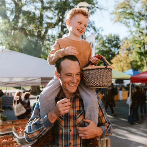 Young Boy with his father at an outdoor market using a small round basket